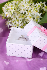 Beautiful box with wedding ring on purple background