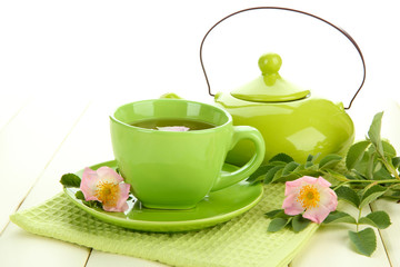 Cup and teapot of herbal tea with hip rose flowers