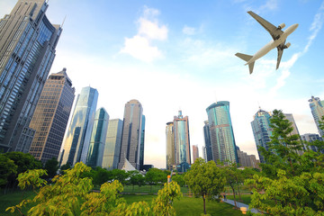 Naklejka premium Aircraft flying over the modern city buildings over
