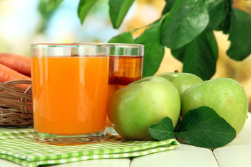 Glasses of juice, apples and carrots