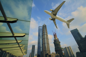 Fototapeta na wymiar Aircraft flying over the modern city buildings over