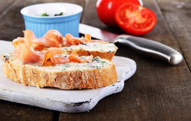 Fish sandwiches on cutting board on wooden table