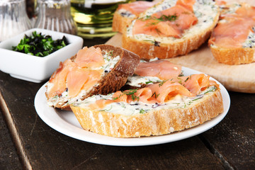 Fish sandwiches on cutting board and plate on wooden table