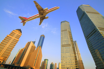 Fototapeta na wymiar Aircraft flying over the modern city buildings over