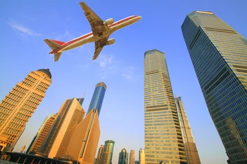 Poster Im Rahmen Aircraft flying over the modern city buildings over © Aania