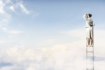 Businesswoman standing on ladder