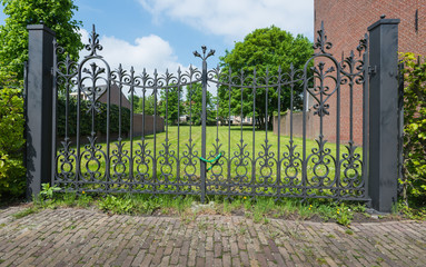 Ornate wrought iron gate with a chain and padlock. - obrazy, fototapety, plakaty