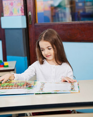 Girl Opening Popup Book At Desk In
