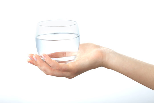 A hand holding a clear glass of water