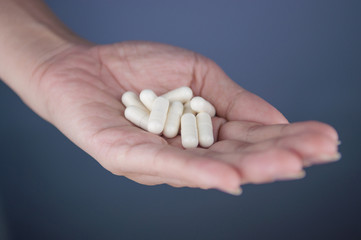 Closed up white capsule on hand