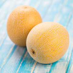 Two ripe Galia melons on wooden boards