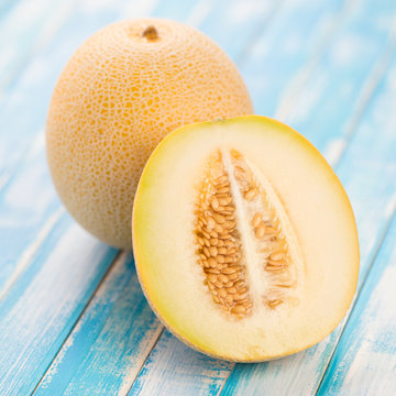 Ripe Galia melon and its half on wooden boards, close-up