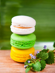A stack of three colorful French macarons on a green background