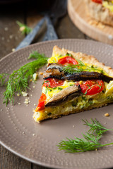 slice of quiche with vegetables and fish, sprats