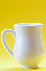 White ceramic milk jug on a yellow background