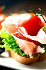 Sandwiches with prosciutto on plate close up