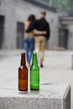 two bottles of beer and couple in the background