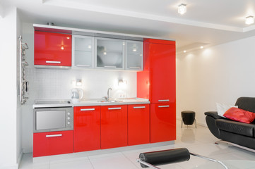 A modern red kitchen, near to a black settee