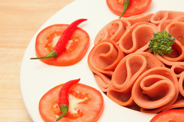 closeup slices of ham on white  plate with tomato and chili