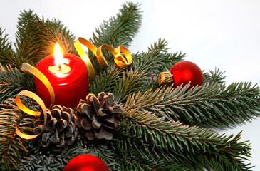 Red candle burning amongst twigs of the spruce