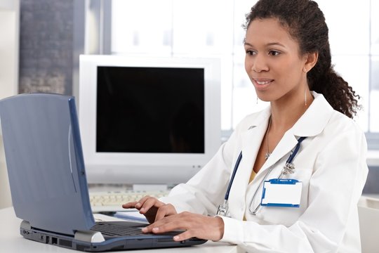 Young doctor working on laptop computer smiling
