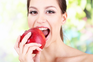 Young woman with apple on bright background