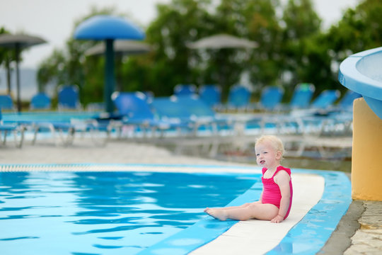 Adorable toddler girl sitting by a swimming pool