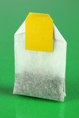 Tea bag on green background