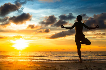 Fototapeta na wymiar Girl practicing yoga by the sea at sunset.