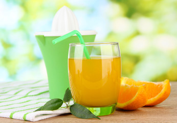 Glass of juice, citrus press and ripe orange
