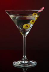 Martini glass with olives on dark red background