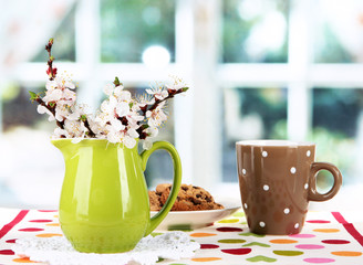 Beautiful blooming branches in pitcher on window background