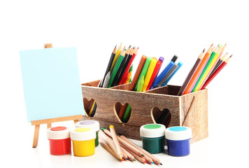 Different pencils in wooden crate, paints and easel, isolated