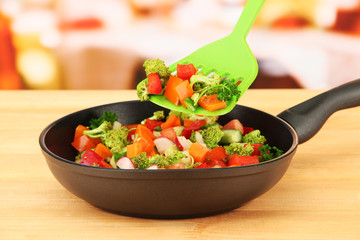 Vegetable ragout in pan,  on wooden table on bright background