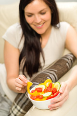 Obraz na płótnie Canvas Joyful woman eating bowl of fresh vegetables