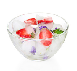 Ice cubes with flowers, strawberry pieces and herbs in bowl,