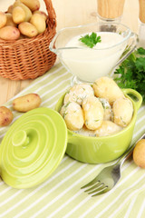 Tender young potatoes with sour cream and herbs in pan
