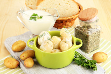 Tender young potatoes with sour cream and herbs in pan