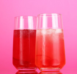 Two cherry cocktails with ice on pink background