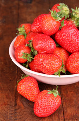 Fresh strawberry in bowl on wooden background