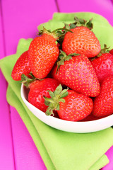 Fresh strawberry in bowl on pink wooden background