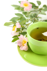 Cup of herbal tea with hip rose flowers, isolated on white