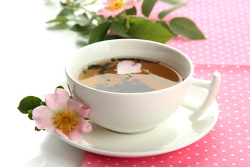 Cup of herbal tea with hip rose flowers, isolated on white