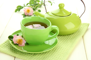Cup and teapot of herbal tea with hip rose flowers