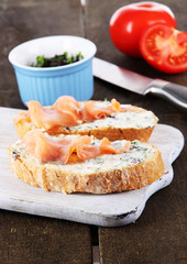 Fish sandwiches on cutting board on wooden table