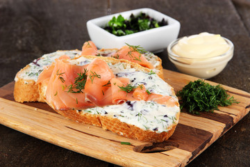 Fish sandwiches on cutting board on wooden table