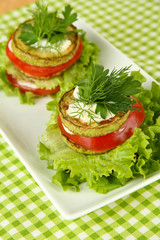 Tasty roasted marrow and tomato slices with salad leaves,