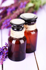Medicine bottles and salvia flowers on purple wooden background