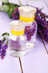 Fototapeta na wymiar Medicine bottles with salvia flowers on purple wooden
