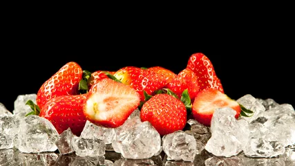 Foto op Plexiglas aardbei op zwarte achtergrond. aardbeien met ijsblokjes erop © EwaStudio